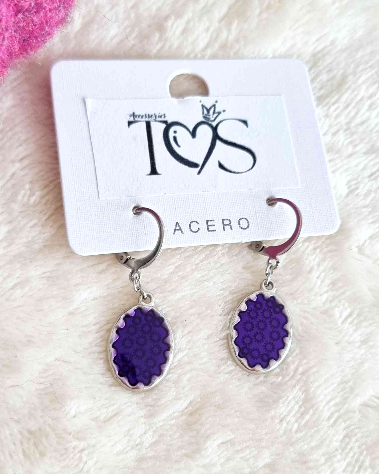 Pendientes Aarau MoradoEncantarás a todos con los pendientes Aarau morado. Su dije en to o berenjena brillante destaca con elegancia femenina. Prácticos pero con un toque de glamour, cada vez que los lleves puedes estar segura de que resaltaras con su bel