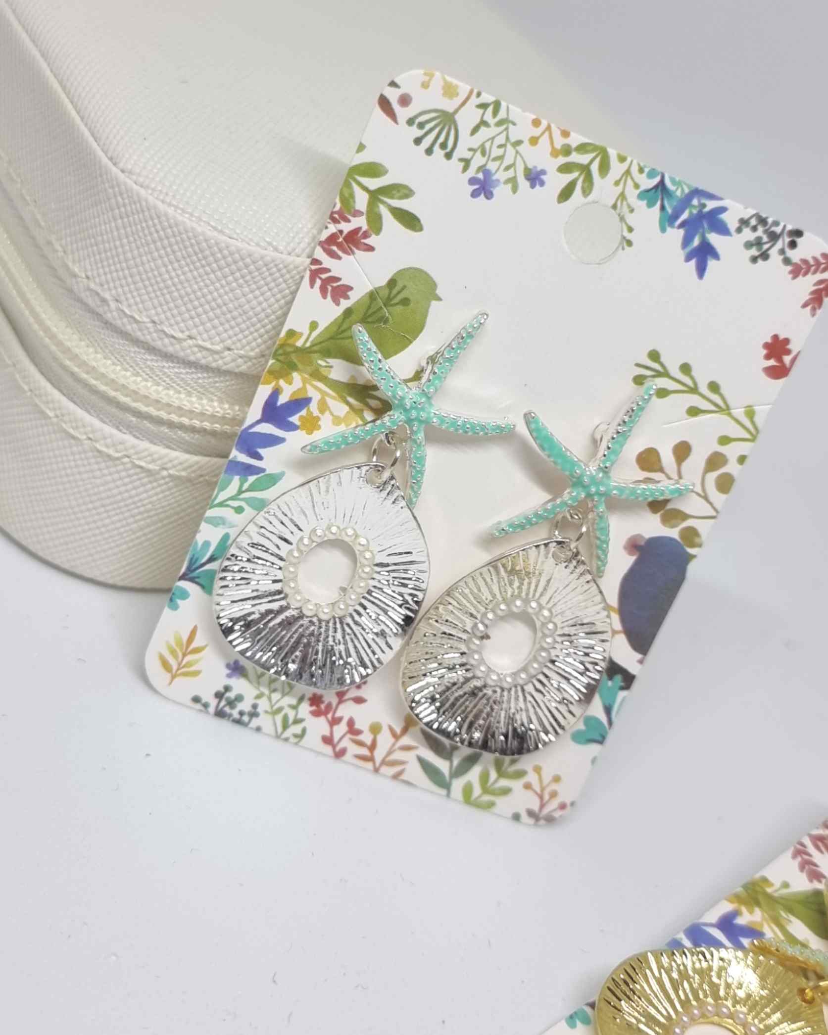 Pendientes Estrella De Mar Perlas PlateadoPendientes estrella de mar ¡Los Pendientes Estrella De Mar Perlas Plateado son la combinación perfecta para conseguir un look de verano! Estos pendientes veraniegos con pequeñas perlas plateadas son una preciosa a
