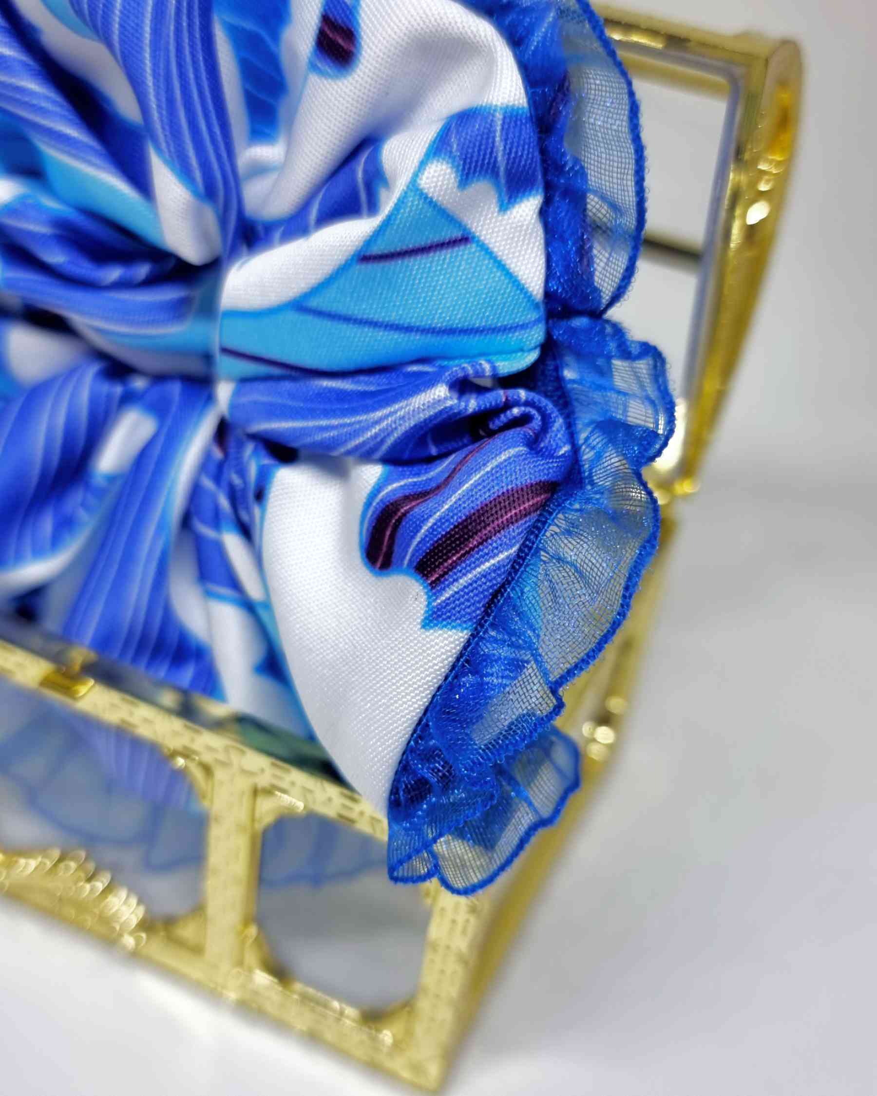 Scrunchie Del Mar | HandmadeColetero Del Mar Descubre un look único y lleno de elegancia con nuestro coletero. Hecho con tejido en tonos azules que evocan los colores del mar y la playa, borde de encaje azul delicado para un acabado sofisticado. Cada uno