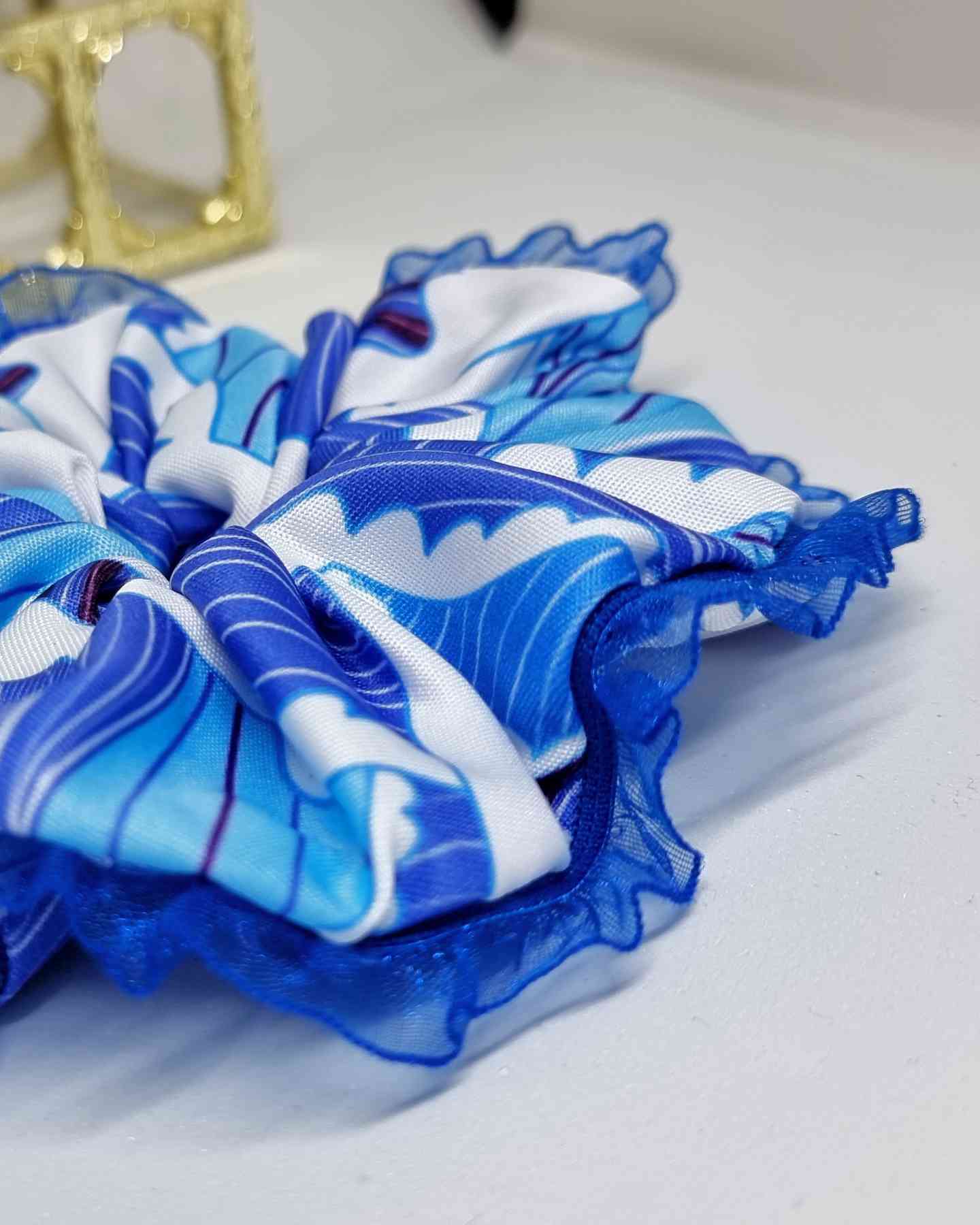 Scrunchie Del Mar | HandmadeColetero Del Mar Descubre un look único y lleno de elegancia con nuestro coletero. Hecho con tejido en tonos azules que evocan los colores del mar y la playa, borde de encaje azul delicado para un acabado sofisticado. Cada uno