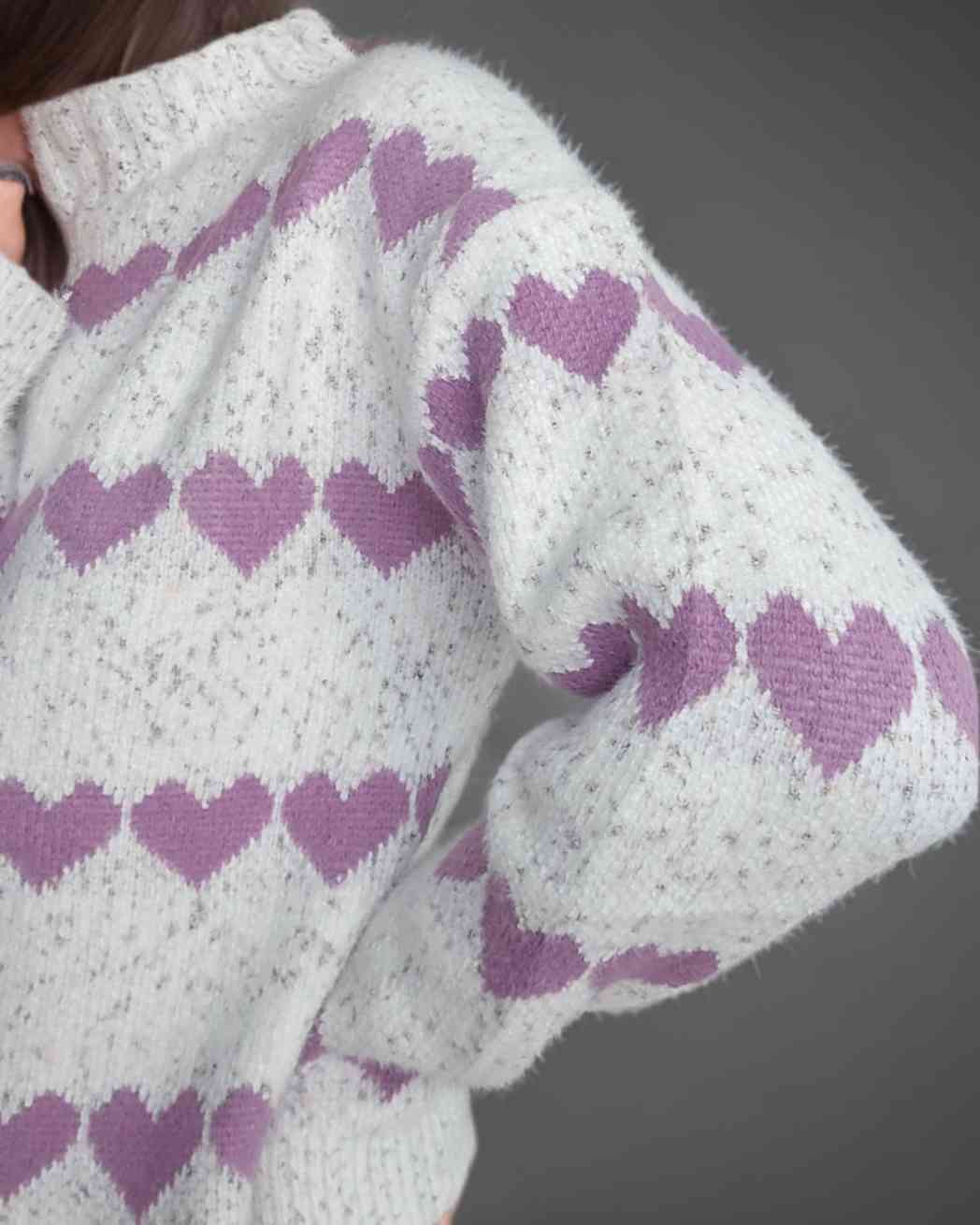 Pullover Jersey Cuori BlancoEste jersey suave cuenta con un diseño de cenefas con corazones en contraste, presentando un estilo único y femenino. Con corazones lila y un fondo jaspeado en tonos blanco, gris y rosa, este jersey es ideal para añadir un toqu