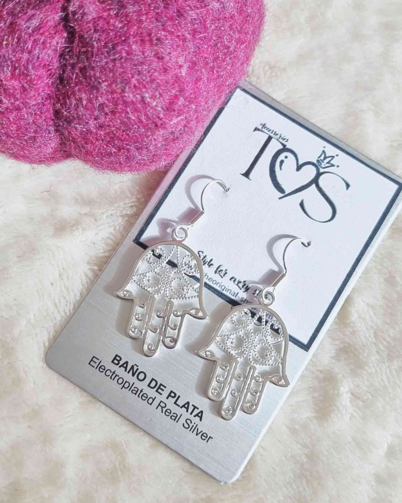 Pendientes Energie Colgantes¡Ensalza tu estilo con los Pendientes Energie Colgantes! Su colgante de mano hamsa o mano de Fatima otorgan un efecto único y refinado. Estos lindos pendientes te protegerán y harán lucir fabulosa con cualquier atuendo. ¡Adorna