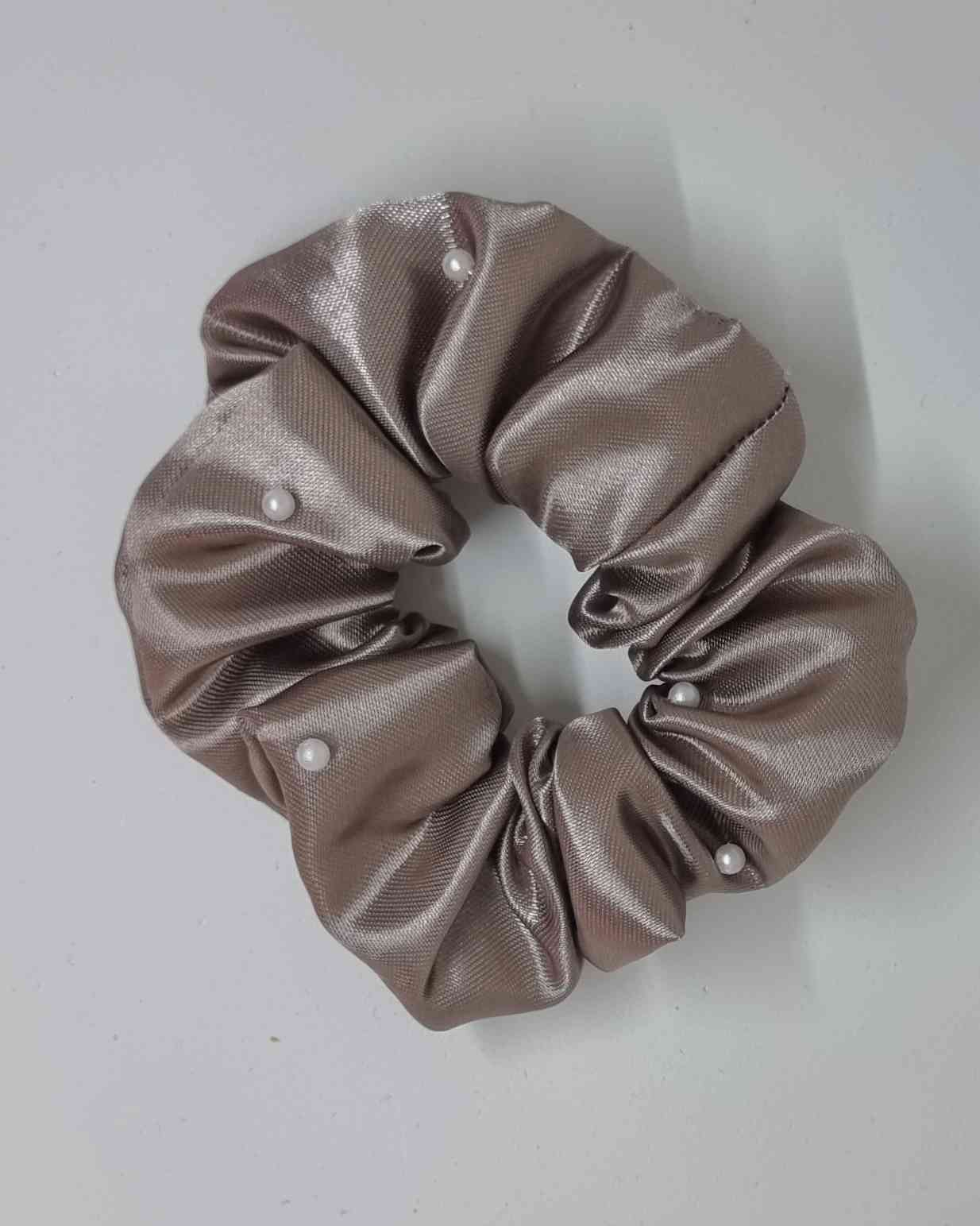 Scrunchie Glam Satin Perlas TaupeColetero Satinado Perlas Taupe Este hermoso scrunchie de satén con perlas es la perfecta combinación para un look femenino y glamuroso. Las perlas son de calidad superior, asegurando detalles duraderos. El scrunchie es hec