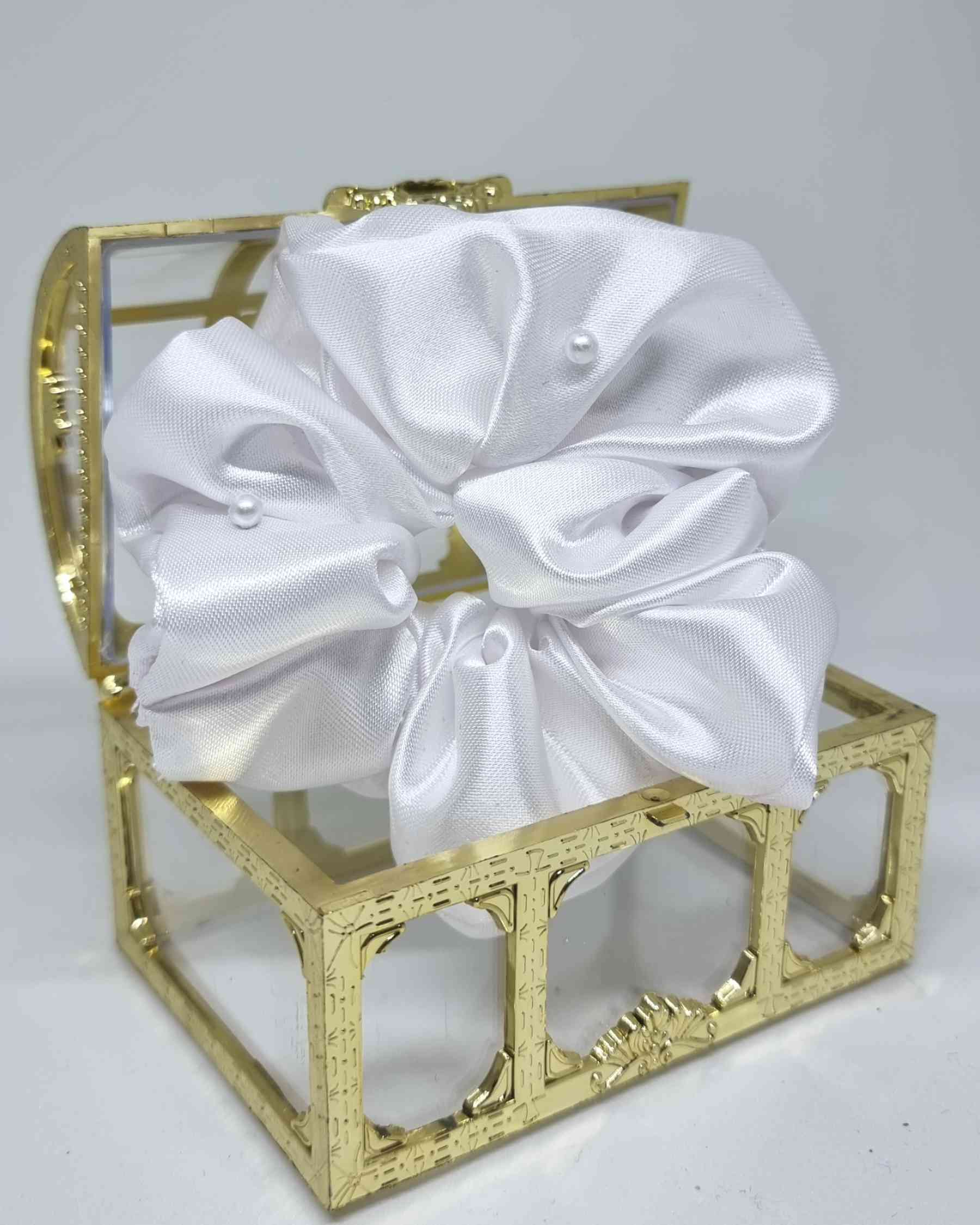 Scrunchie Glam Satin Perlas BlancoEste hermoso scrunchie de satén con perlas es la perfecta combinación para un look femenino y glamuroso. Las perlas son de calidad superior, asegurando detalles duraderos. El scrunchie es hecho a mano, con un tamaño de 12