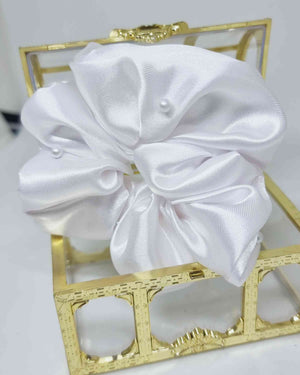Scrunchie Glam Satin Perlas BlancoEste hermoso scrunchie de satén con perlas es la perfecta combinación para un look femenino y glamuroso. Las perlas son de calidad superior, asegurando detalles duraderos. El scrunchie es hecho a mano, con un tamaño de 12