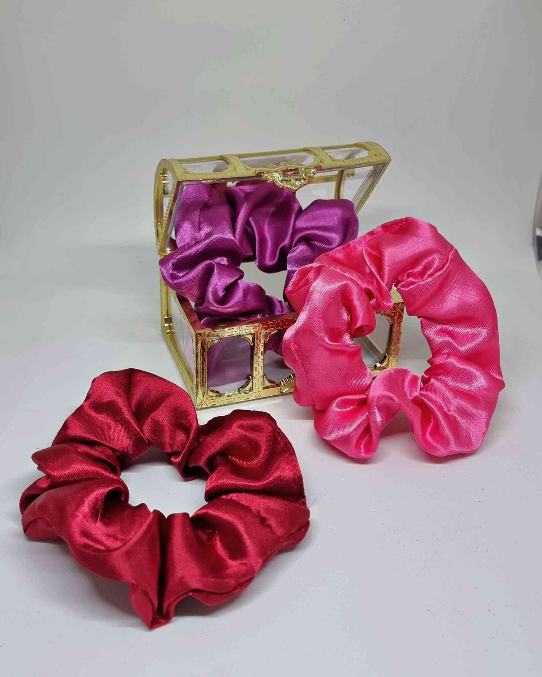 Scrunchies Box Satinado RosesColeteros Box Satinados Roses ¡Elige la diferencia con nuestra caja de scrunchies satinados en tonos rosados! Estos coleteros satinados de 10 cm, cuidadosamente hechos a mano, mimarán tu cabello evitando que se dañe y el encre