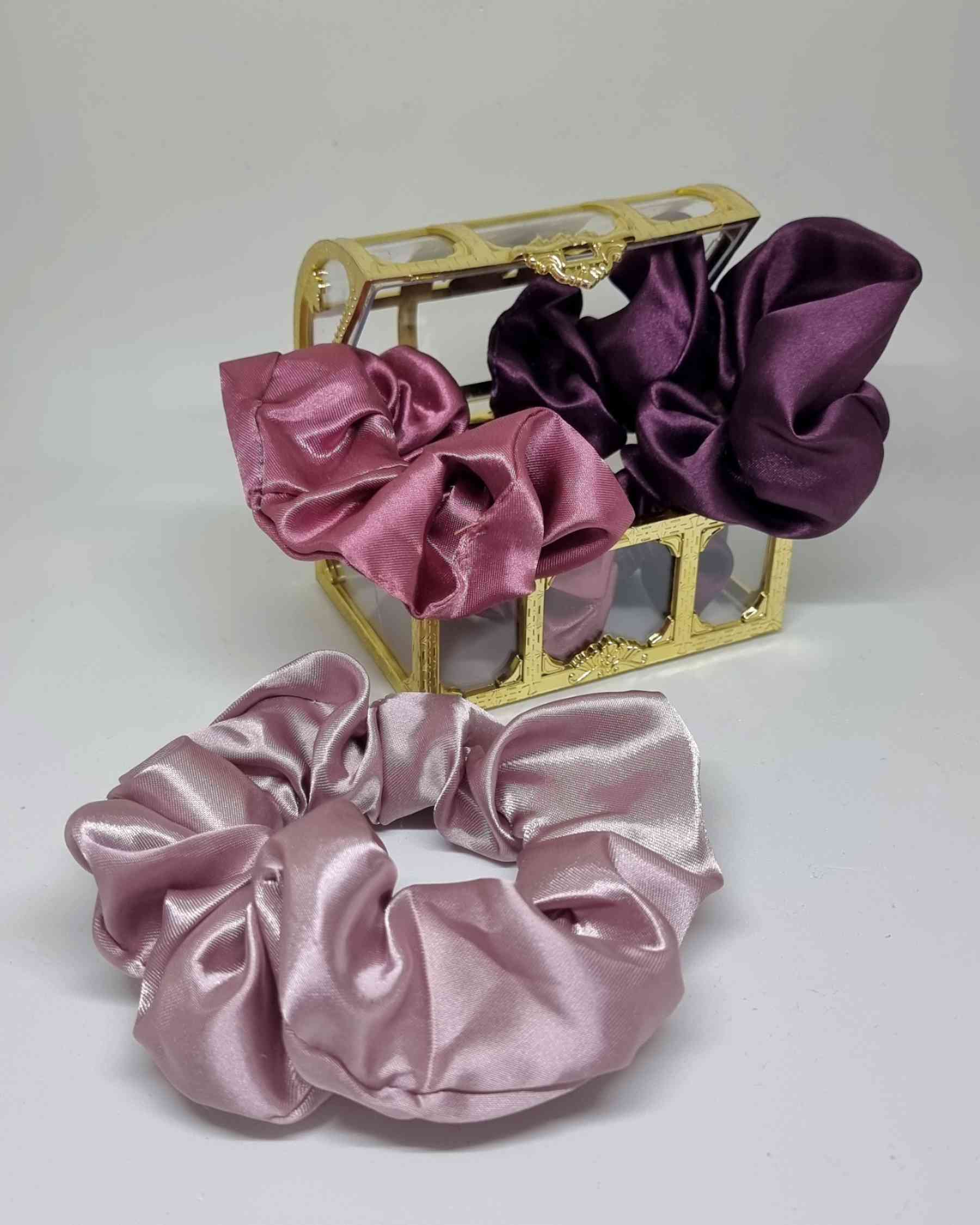 Scrunchie Box Satin Perlado LilaScrunchie Box Satin Perlado ¡Aprovecha este maravilloso set de 3 scrunchie box satin perlado lila para cuidar tu cabello y destacar tu estilo! Hechos a mano, con tamaño de 12 cm, estos coleteros son la opción perfecta para