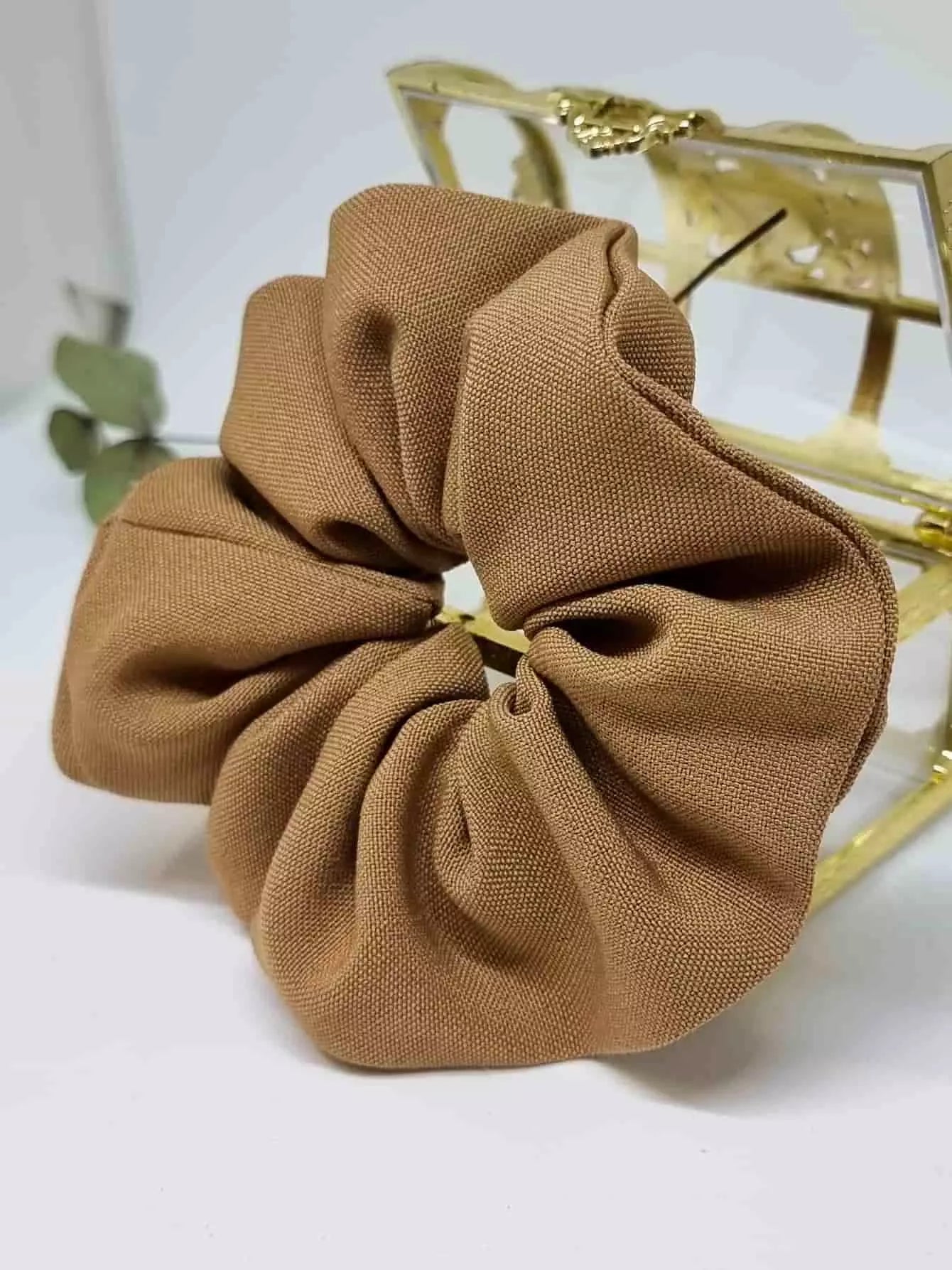 Scrunchie Castaño - Selección OtoñoColetero selección otoño El scrunchie de tono camel hecho a mano con detalles artesanales es la prenda ideal para esta temporada de otoño. Suave y práctico, cuida tu melena sin dañarla mientras te ofrece un estilo único