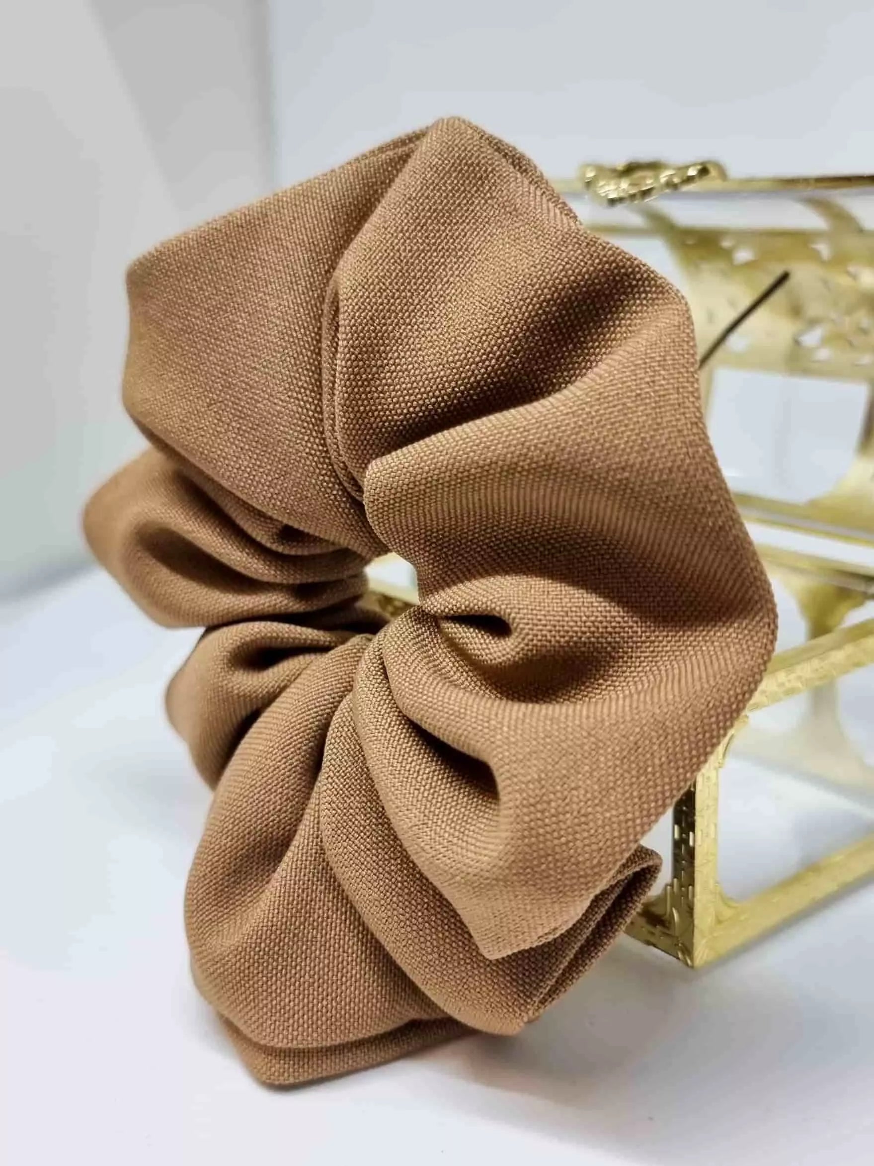 Scrunchie Castaño - Selección OtoñoColetero selección otoño El scrunchie de tono camel hecho a mano con detalles artesanales es la prenda ideal para esta temporada de otoño. Suave y práctico, cuida tu melena sin dañarla mientras te ofrece un estilo único