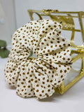 Scrunchie Lucerna - Selección OtoñoColetero Lucerna- Selección Otoño Adorna tu peinado con este coletero artesanal. Está hecho de suave algodón y con un moderno estampado de flores marrones sobre fondo crema. Estas Scrunchies cuidan tu cabello evitando da