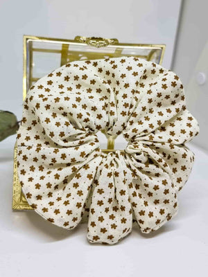 Scrunchie Lucerna - Selección OtoñoColetero Lucerna- Selección Otoño Adorna tu peinado con este coletero artesanal. Está hecho de suave algodón y con un moderno estampado de flores marrones sobre fondo crema. Estas Scrunchies cuidan tu cabello evitando da