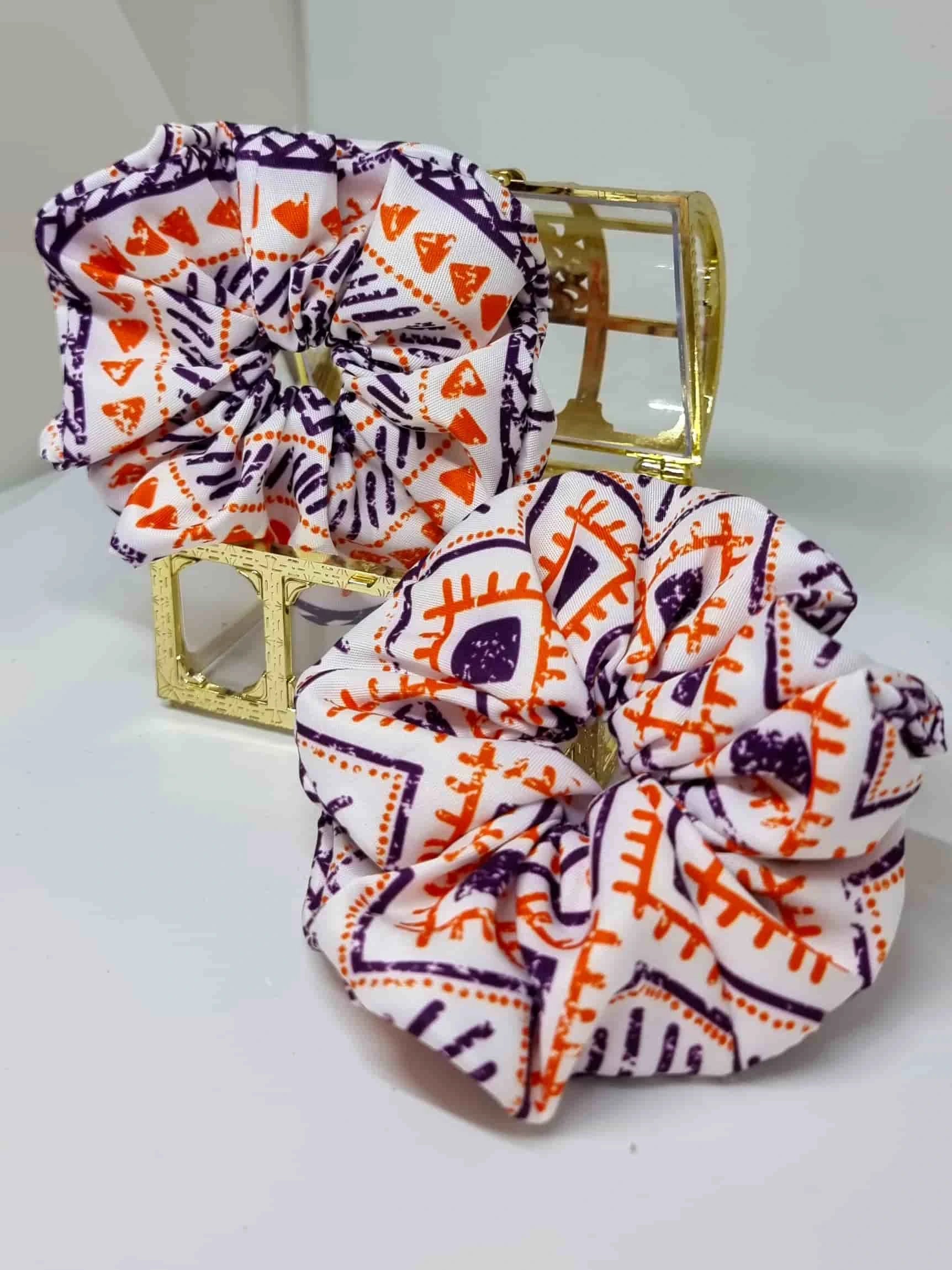 Scrunchie Ethnic Style - Selección OtoñoColetero Étnico Selección Otoño ¡Añade estilo a tu look con este Scrunchie étnico estampado! Esta selección moderniza tu look con hermosos tonos y un estampado vibrante en tonos morado y naranja. ¡Estas tonalidades