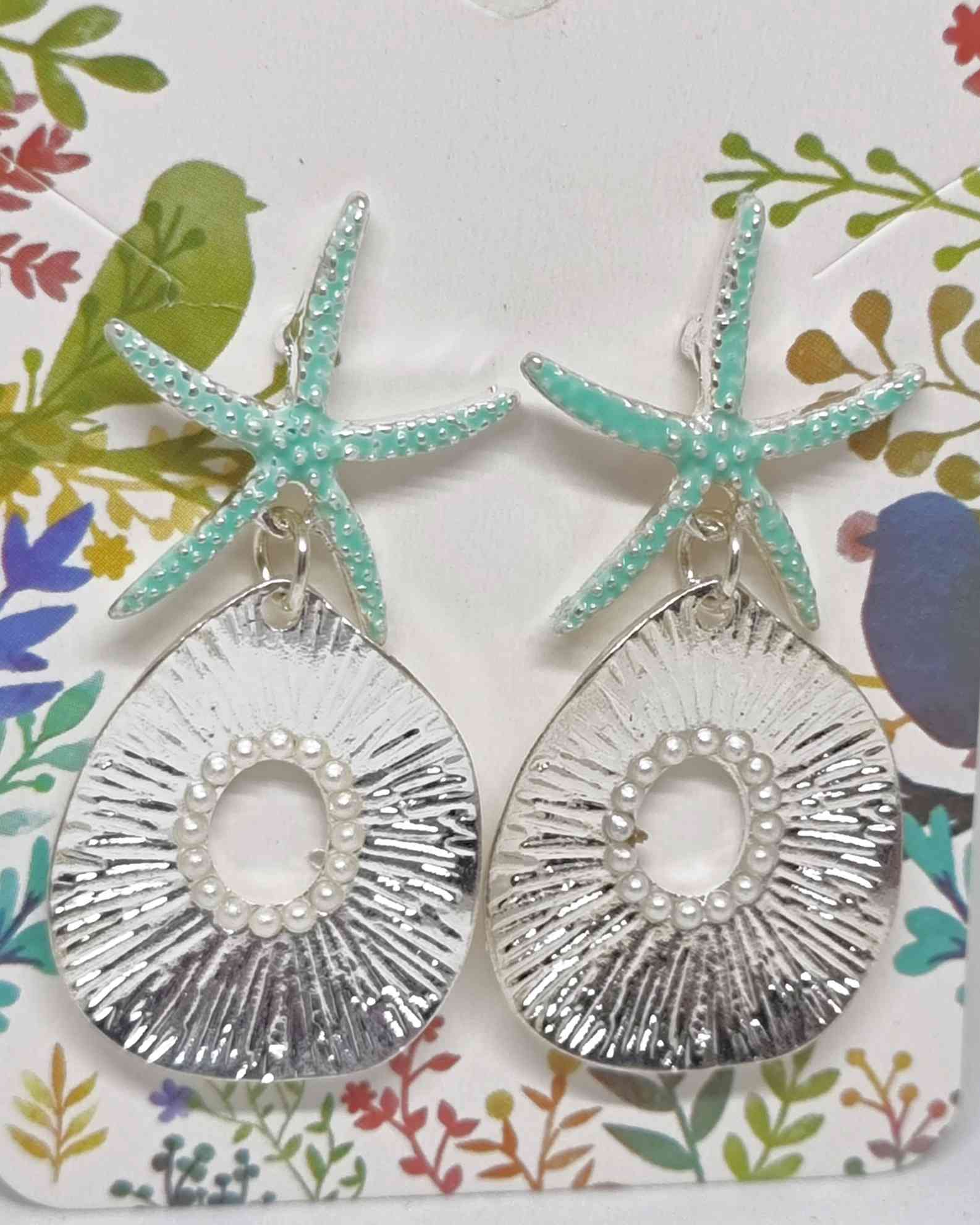 Pendientes Estrella De Mar Perlas PlateadoPendientes estrella de mar ¡Los Pendientes Estrella De Mar Perlas Plateado son la combinación perfecta para conseguir un look de verano! Estos pendientes veraniegos con pequeñas perlas plateadas son una preciosa a